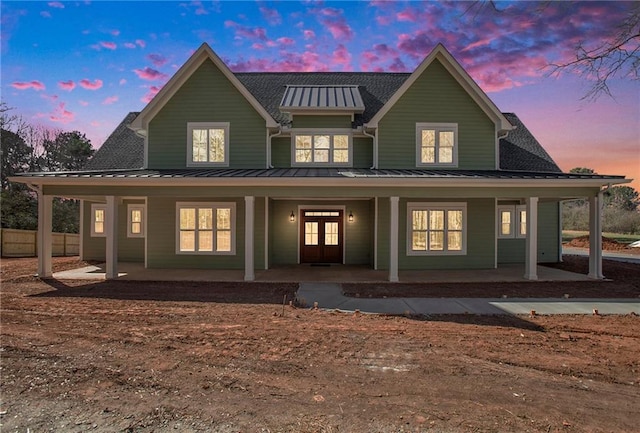 rear view of property featuring a porch, a standing seam roof, fence, and french doors