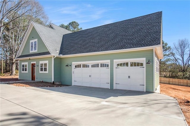 view of front facade featuring a garage, driveway, fence, and roof with shingles