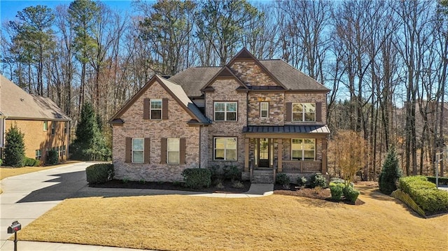 craftsman inspired home featuring a front lawn, a porch, and brick siding