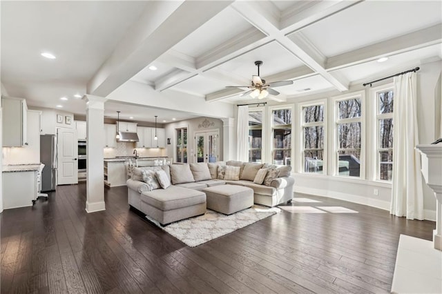 living room featuring decorative columns, beam ceiling, coffered ceiling, and dark wood-type flooring