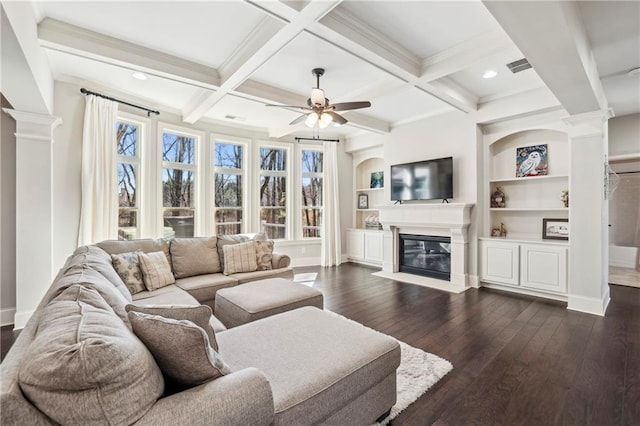 living room featuring dark wood finished floors, beam ceiling, a glass covered fireplace, and decorative columns