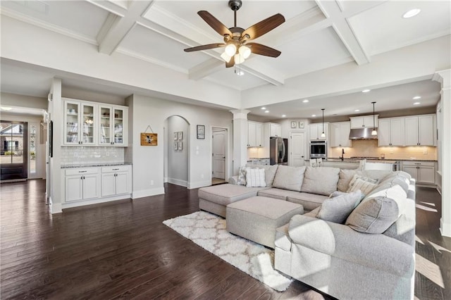 living room featuring dark wood-style floors, baseboards, arched walkways, and coffered ceiling