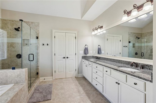 full bathroom featuring double vanity, a shower stall, a closet, and a sink