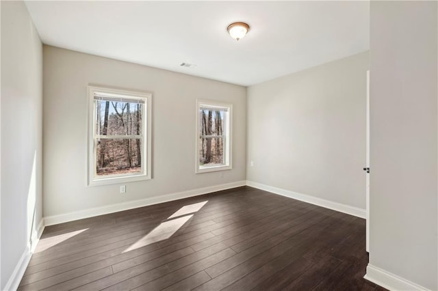 unfurnished room with baseboards and dark wood-type flooring