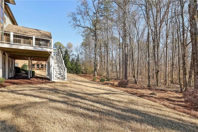 view of yard featuring driveway, a sunroom, and stairway