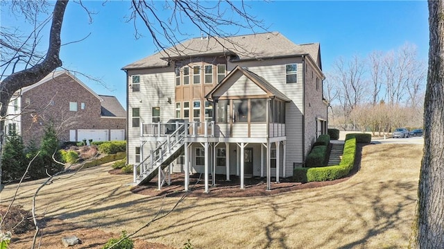 back of house featuring a sunroom, stairway, a deck, and a lawn