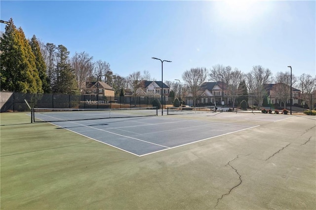 view of tennis court with fence and a residential view