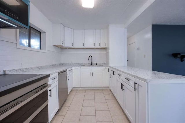 4618 Conner Rd, Columbus, GA 31903 - kitchen with stainless steel appliances, a peninsula, white cabinetry, light tile patterned floors, and light stone countertops