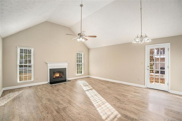 unfurnished living room featuring a textured ceiling, light wood-type flooring, vaulted ceiling, and ceiling fan with notable chandelier