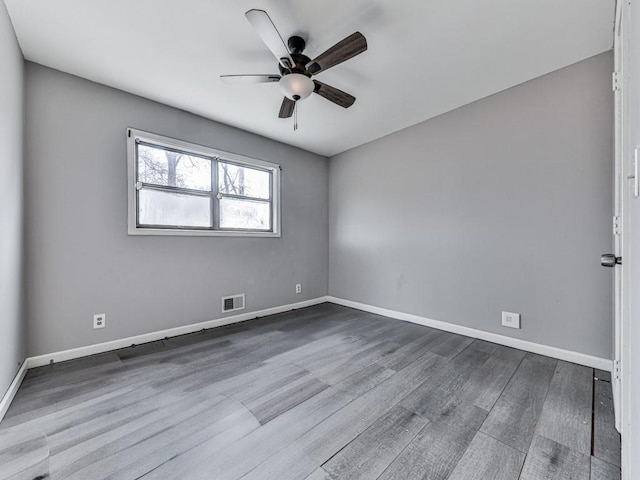 empty room with visible vents, baseboards, dark wood finished floors, and a ceiling fan