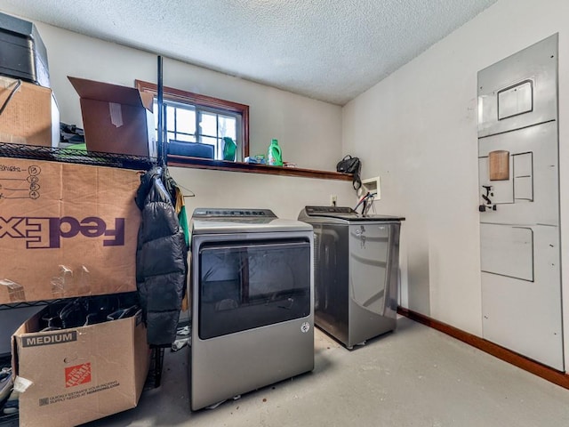 laundry area with laundry area, washing machine and dryer, a textured ceiling, and baseboards