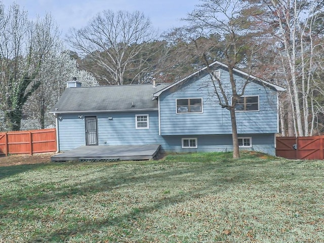 rear view of property featuring a wooden deck, a yard, and fence