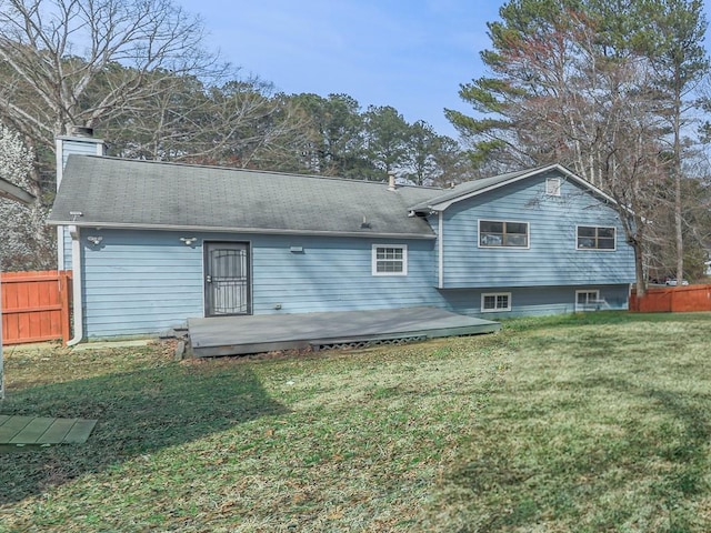 back of property featuring a wooden deck, a yard, fence, and a chimney