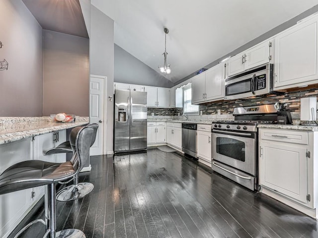 kitchen featuring tasteful backsplash, dark wood-type flooring, lofted ceiling, appliances with stainless steel finishes, and white cabinetry