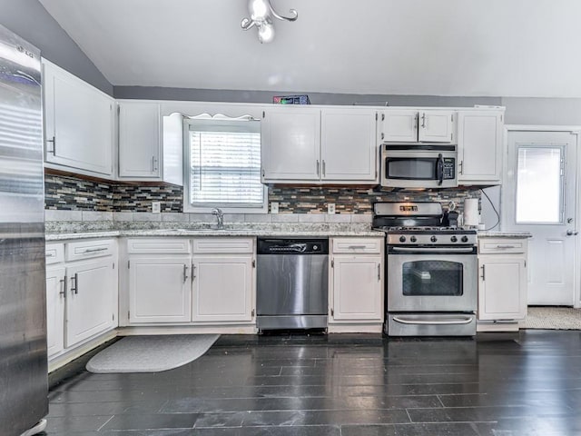 kitchen featuring lofted ceiling, white cabinets, tasteful backsplash, and stainless steel appliances