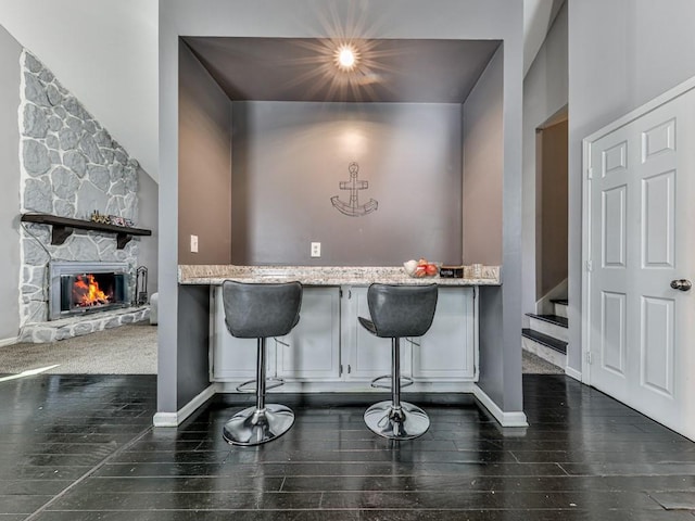 interior space with a stone fireplace, stairs, wood finished floors, and baseboards