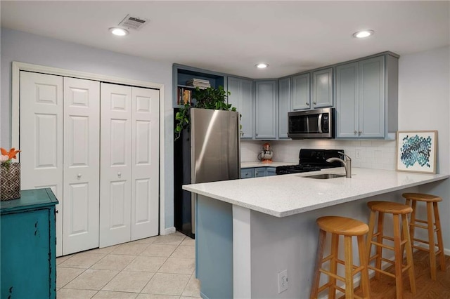 1445 Monroe Dr NE Unit C13, Atlanta, GA 30324 - kitchen with stainless steel appliances, a peninsula, a breakfast bar, gray cabinets, and backsplash