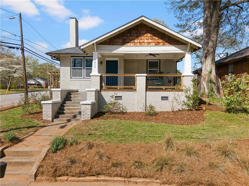 view of front of home featuring a front yard, brick siding, a porch, and a chimney