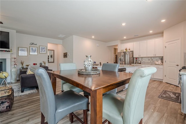 dining space with light wood finished floors and recessed lighting