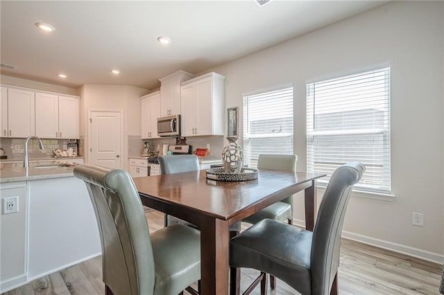 dining space with light wood-style floors, recessed lighting, and baseboards