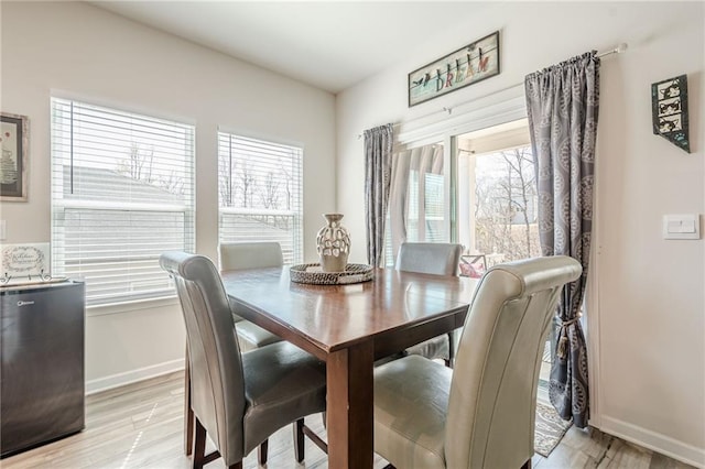 dining space with plenty of natural light, light wood-style floors, and baseboards