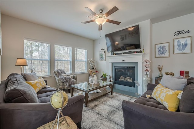 living room with a ceiling fan and a glass covered fireplace