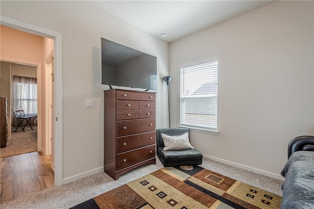 sitting room with baseboards and light carpet