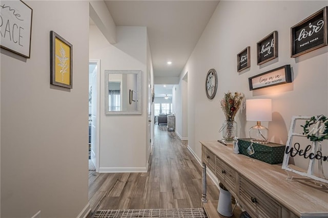 corridor with recessed lighting, wood finished floors, and baseboards