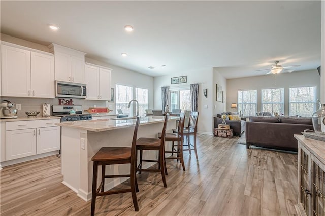 kitchen with appliances with stainless steel finishes, a sink, light wood-style floors, plenty of natural light, and recessed lighting