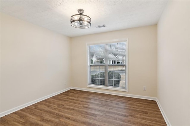 unfurnished room with dark wood-type flooring and a textured ceiling