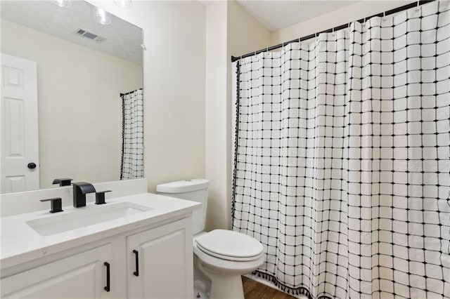 bathroom with vanity, a textured ceiling, toilet, and walk in shower