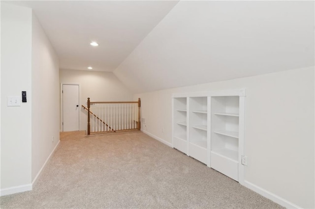 additional living space featuring vaulted ceiling and light carpet