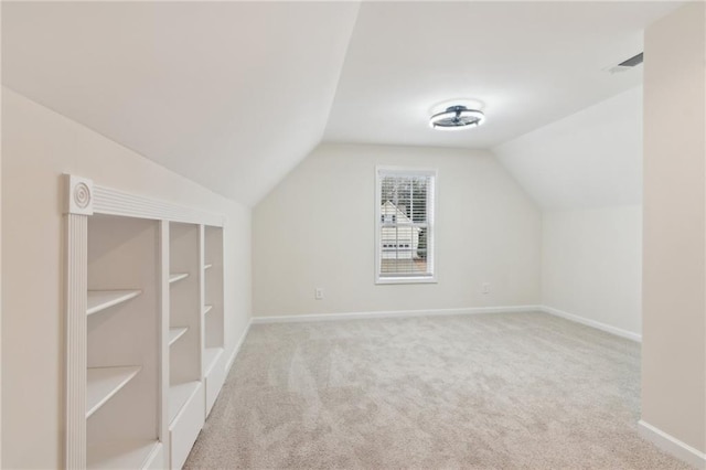 bonus room with lofted ceiling and light colored carpet