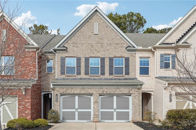 view of property featuring brick siding, an attached garage, and driveway