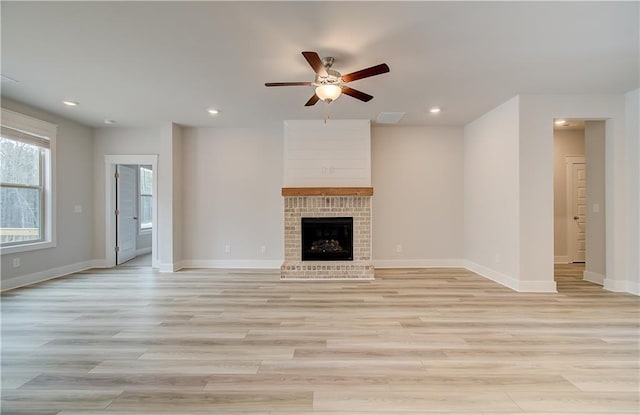 unfurnished living room featuring a brick fireplace, baseboards, and light wood finished floors