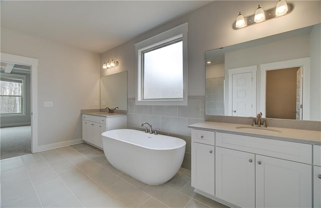 bathroom with two vanities, a sink, a freestanding bath, and tile patterned floors