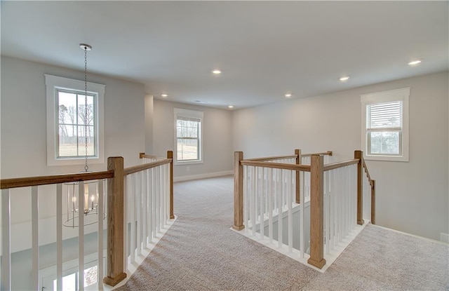 hall with a chandelier, recessed lighting, light colored carpet, an upstairs landing, and baseboards