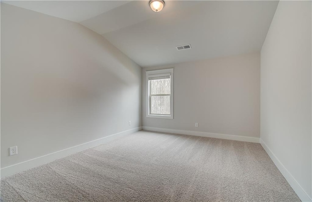 empty room featuring carpet floors, visible vents, vaulted ceiling, and baseboards