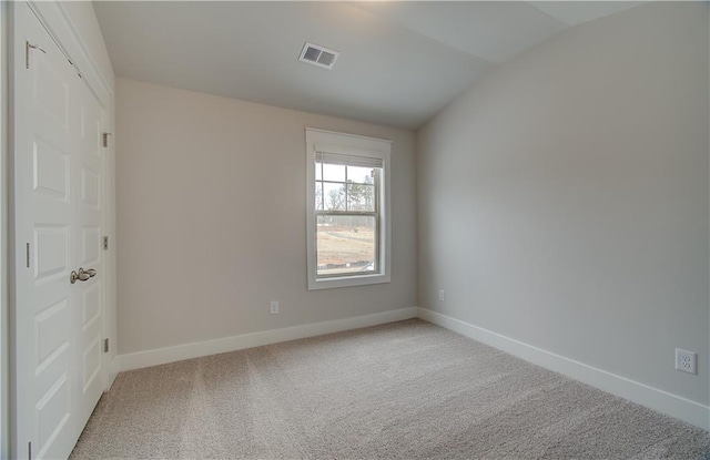 empty room with carpet floors, baseboards, visible vents, and lofted ceiling