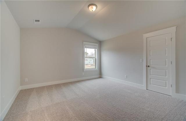 empty room with lofted ceiling, carpet floors, visible vents, and baseboards