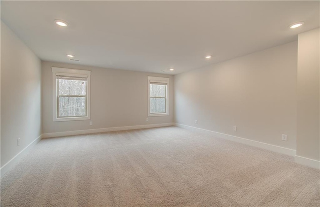 spare room with recessed lighting, light colored carpet, and baseboards