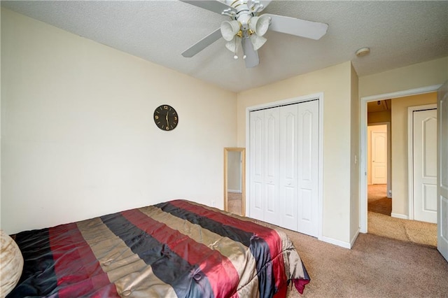 carpeted bedroom with a textured ceiling, a closet, a ceiling fan, and baseboards