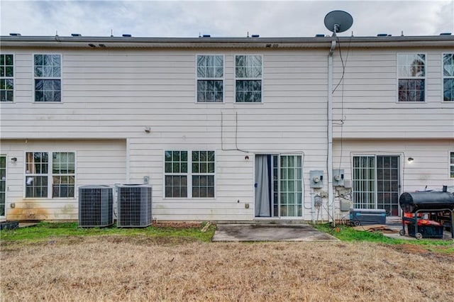 back of property with solar panels, a patio area, and central air condition unit