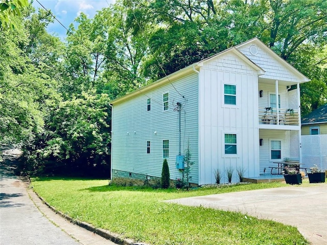 view of side of home featuring a balcony and a lawn