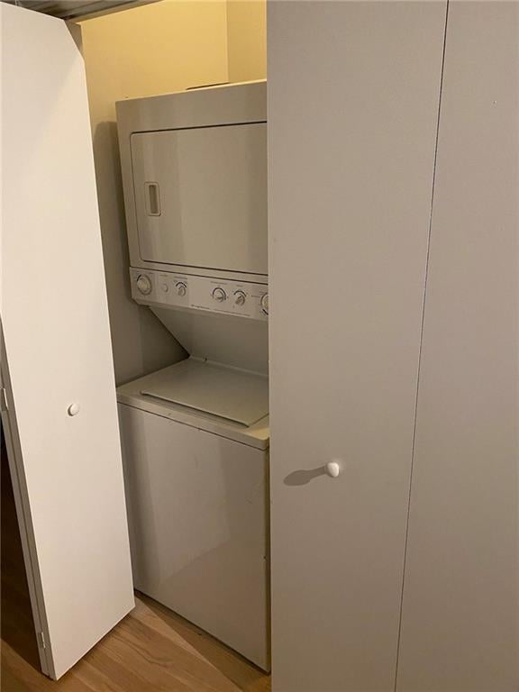 clothes washing area featuring stacked washer and clothes dryer and light hardwood / wood-style floors