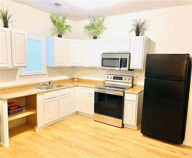 kitchen featuring white cabinetry, sink, light hardwood / wood-style floors, and appliances with stainless steel finishes