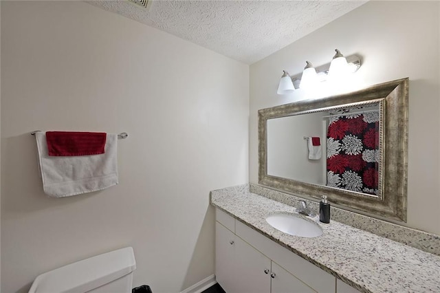 bathroom with toilet, vanity, and a textured ceiling