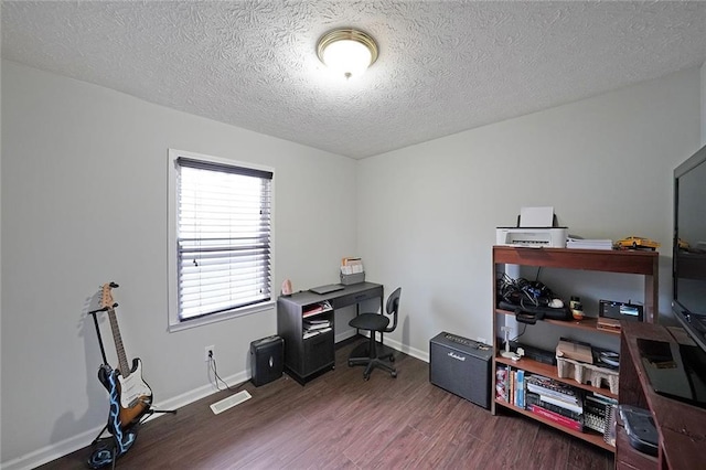 office area with a textured ceiling, wood finished floors, visible vents, and baseboards