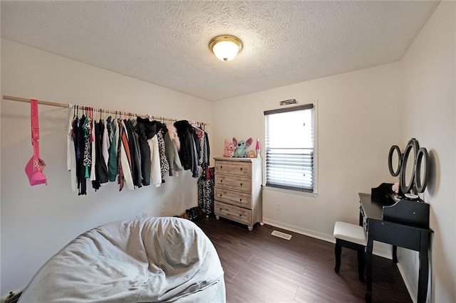 bedroom featuring visible vents, a textured ceiling, dark wood-type flooring, and baseboards