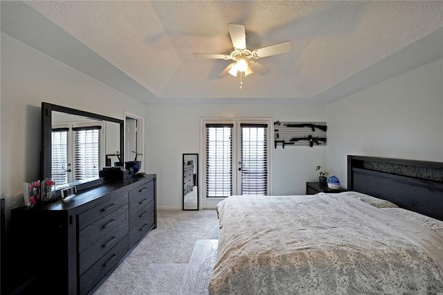 bedroom featuring ceiling fan, light colored carpet, french doors, a textured ceiling, and a raised ceiling